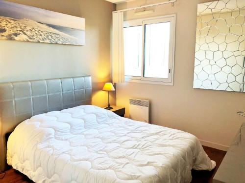 une chambre avec un grand lit blanc avec une fenêtre dans l'établissement LUCIA appartement standing vue bassin, à Arcachon