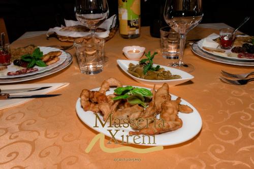 a table with plates of food and glasses of wine at Masseria Xireni in Castellana Sicula