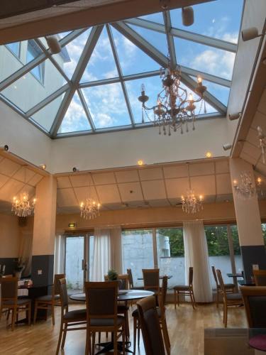 a dining room with a large skylight and tables and chairs at Mitt hotell & apartments in Moss