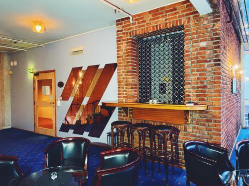 a bar with black chairs and a brick wall at Mitt hotell & apartments in Moss
