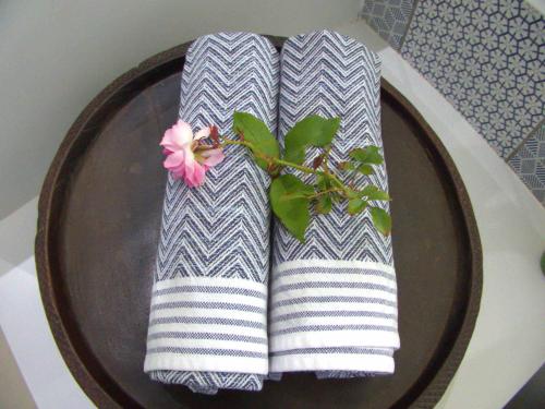 two towels on a plate with a flower on it at Long Story Guest House in Plettenberg Bay