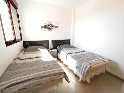 2 lits se trouvent dans une chambre aux murs blancs. dans l'établissement Modern apartment with large terrace in Mojon Hills, à Carthagène