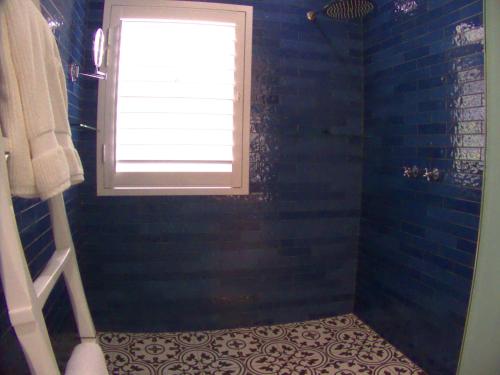 a bathroom with a window and a blue shower at Long Story Guest House in Plettenberg Bay
