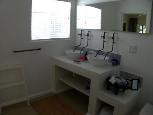 a bathroom with two sinks and a mirror at Long Story Guest House in Plettenberg Bay