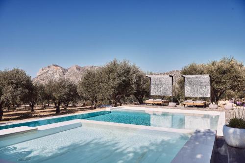 una piscina con alberi e montagne sullo sfondo di Villa Carpos a Chania