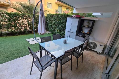 a table and chairs on a patio with an umbrella at Le Lodge, T2 classé 3 étoiles avec jardin, parking, piscine & mer à 2 pas in Menton