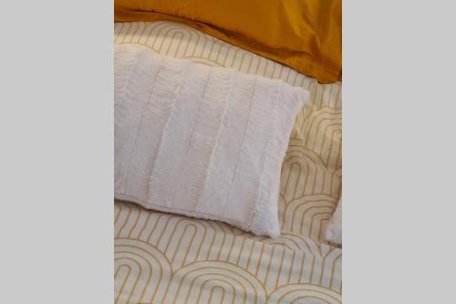 a bed with a white pillow on top of it at Le Lodge, T2 classé 3 étoiles avec jardin, parking, piscine & mer à 2 pas in Menton