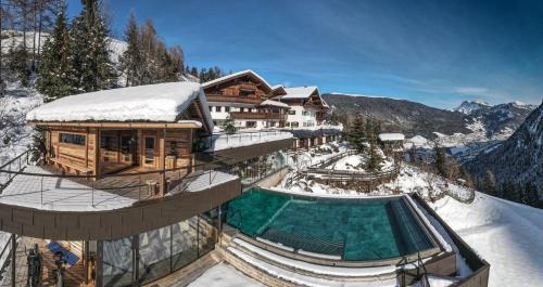 a building in the snow with a swimming pool at Charmehotel Uhrerhof - Deur in Ortisei