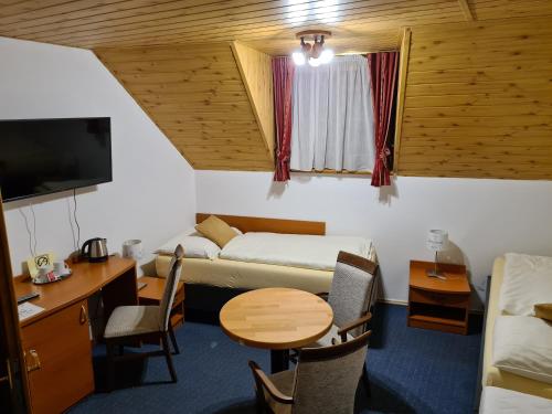 Zimmer mit einem Bett, einem Schreibtisch und einem Tisch in der Unterkunft Ferdinand Penzion in Moldava nad Bodvou