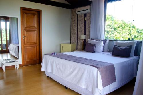 a bedroom with a large bed with a large window at Ilha Branca Exclusive Hotel in Búzios