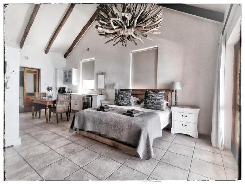 a bedroom with a bed and a table and a chandelier at Kleinzee Oceanfront Guesthouse in Gansbaai
