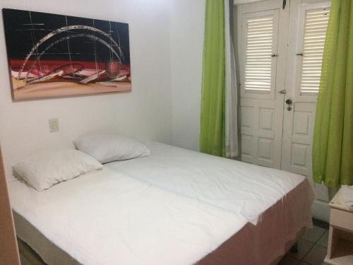 una camera da letto con un letto con lenzuola bianche e tende verdi di Ape lindo em Porto - Oxente reserve logo a Porto Seguro