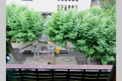 een balkon met uitzicht op een gebouw met bomen bij Appt 2 étoiles agréable et calme vue sur montagnes in Amélie-les-Bains-Palalda