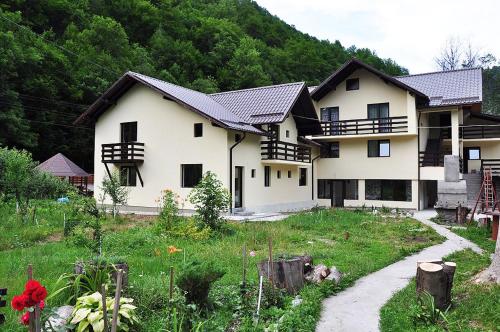 a large white house with a garden in front of it at Pensiunea Ciobanelu in Malaia