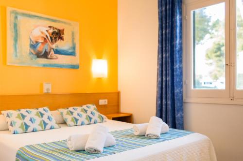 a hotel room with two beds and a window at Apartamentos Vista Playa I in Cala Blanca