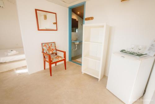 ein Wohnzimmer mit einem Stuhl und ein Badezimmer in der Unterkunft Mangabeira Logde in Ilha de Boipeba