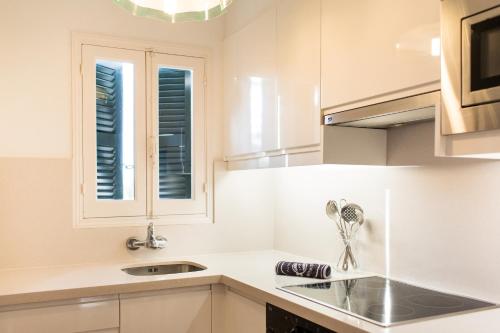 una cucina bianca con lavandino e finestra di Sagitario Vista Playa II Apartamentos a Cala Blanca
