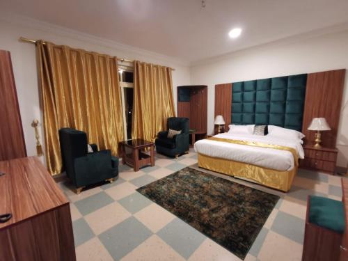 a hotel room with a bed and two chairs at الزمردة للشقق المخدومة in Ash Shuqayq