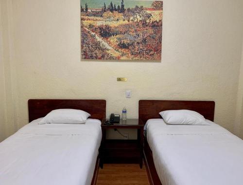 - 2 lits installés à côté d'un bureau dans une chambre dans l'établissement Hotel Capri de Leon Mexico, à León