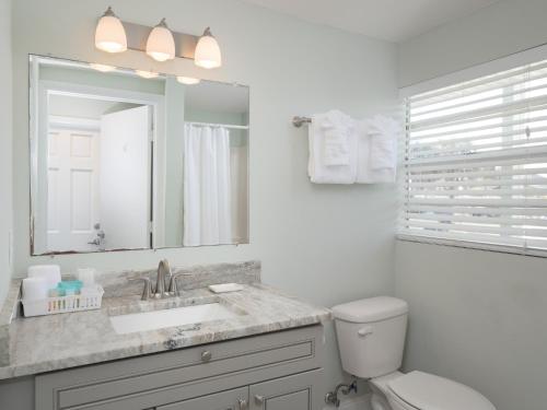 W łazience znajduje się umywalka, toaleta i lustro. w obiekcie Sea Aire Oceanfront Inn w mieście Cocoa Beach