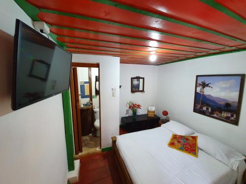 a bedroom with a bed and a flat screen tv at Hostal Estrella de Agua in Salento