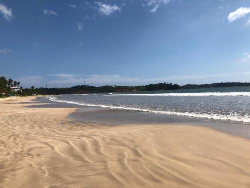 a beach with sand and water on a sunny day at Villa The Leaf in Weligama