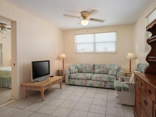 a living room with a couch and a tv at Sea Aire Oceanfront Inn in Cocoa Beach