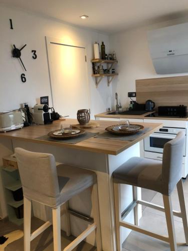 een keuken met een eiland met 2 stoelen en een aanrecht bij Studio tout neuf. Court séjour, loisirs, professionnel in Chaudfontaine