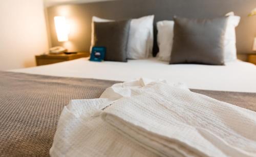 una camera da letto con letto, lenzuola e cuscini bianchi di Blue Tree Towers All Suites Santo André a Santo André