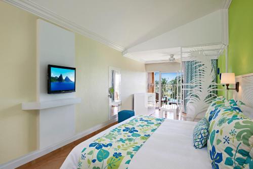 Coconut Bay Beach Resort & Spa All Inclusive في فيو فورت: غرفة نوم بسرير وتلفزيون على جدار