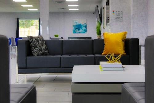 a living room with a black couch with yellow pillows at Home Inn and Suites Olive Branch in Olive Branch