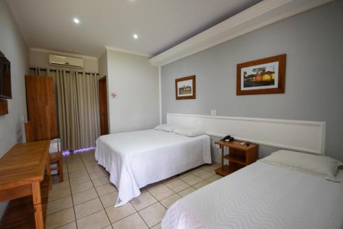 una camera d'albergo con due letti e un tavolo di HOTEL ABAPORU a Adamantina