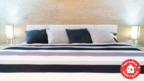 1 cama blanca grande con almohadas azules y blancas en ECONOSUITES FUNDIDORA en Monterrey