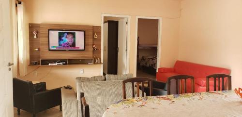 sala de estar con TV, sofá y sillas en Casa em Bombinhas zimbros, en Bombinhas