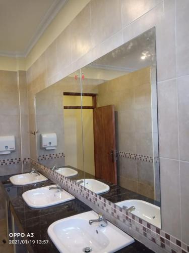 a bathroom with four sinks and a large mirror at The Willis Hotel, Bomet in Bomet