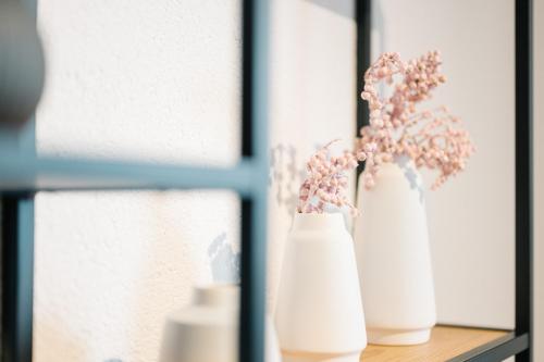 two white vases with flowers sitting on a shelf at Moderne 3 Zi.-FeWo Scandi Style 70 qm Nähe Freiburg in Simonswald
