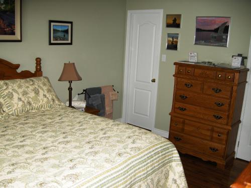a bedroom with a bed and a dresser at Tucked Inn the Harbour B&B in Victoria Harbour