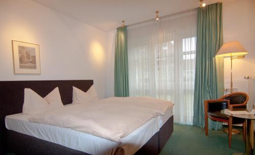 a hotel room with a large bed and a large window at Parkhotel Unter den Linden in Halberstadt