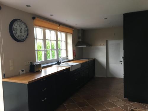 a kitchen with a sink and a clock on the wall at Gertrude&Friends in Herbais