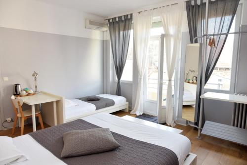 sypialnia z 2 łóżkami, stołem i oknem w obiekcie Cafe de Paris w mieście Capdenac-Gare
