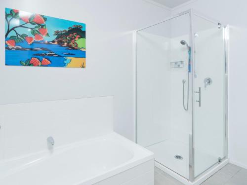 un bagno bianco con doccia e un dipinto sul muro di Skipper's Haven - Opua Holiday Home a Opua