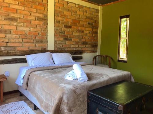 a bedroom with a bed with towels on it at Reserva Três Picos Chalés in Nova Friburgo