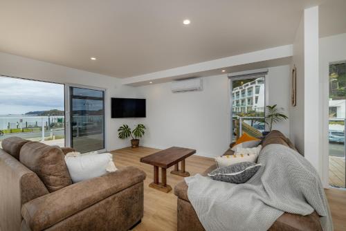 a living room with two couches and a table at Waterfront Beach House - Paihia Holiday Home in Paihia