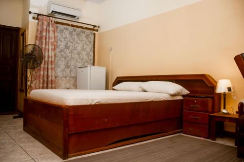 een slaapkamer met een groot houten bed en een dressoir bij Sampson's Guesthouse Company Ltd. in Kwashieman