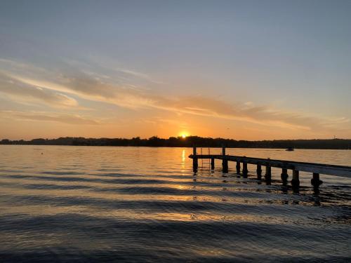 a dock on a lake with the sun setting at Sealand Lake House Stunning Absolute Waterfront in Fishing Point