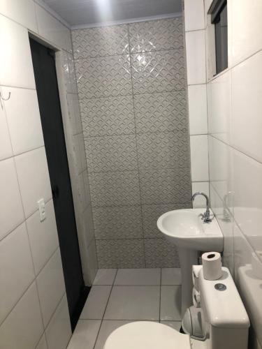 a white bathroom with a toilet and a sink at Pousada Ambiente Familiar in Ponte Alta do Tocantins