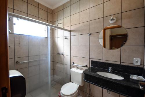 ein Badezimmer mit einem WC, einem Waschbecken und einem Spiegel in der Unterkunft HOTEL ABAPORU in Adamantina