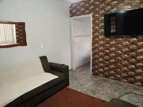 un soggiorno con divano e TV a parete di Casa em Olímpia a Olímpia
