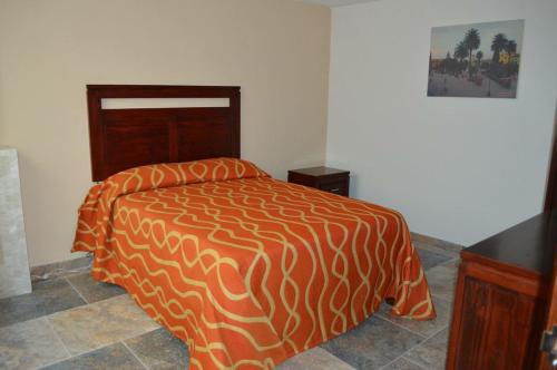 1 cama con edredón naranja y blanco en una habitación en Hotel Suites Don Miguel, en Tlatlauquitepec