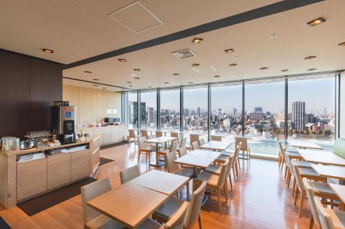 a restaurant with tables and chairs and large windows at Hotel Crown Hills Ueno Premier in Tokyo